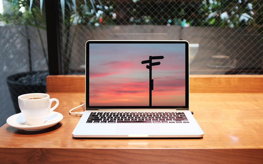 macbook laptop on desk with direction signs image on display